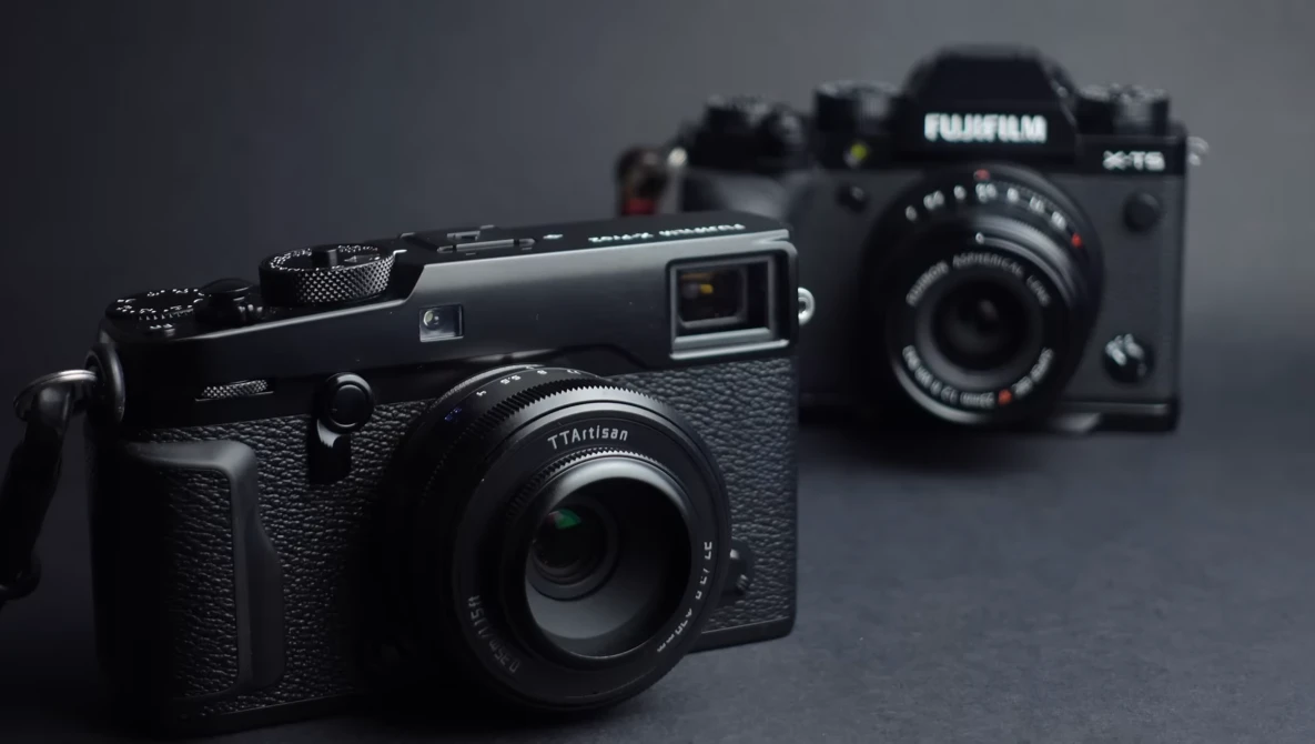 Three rangefinder cameras arranged on a gray surface with selective focus on the nearest black camera.