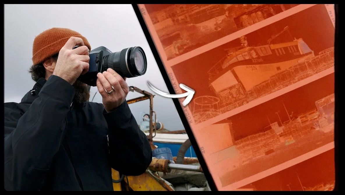 Photographer holding DSLR camera with telephoto lens, wearing brown beanie and dark jacket, positioned in front of orange industrial structure.