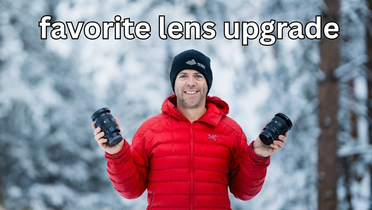 Photographer holding two telephoto lenses in snowy forest setting wearing red jacket.