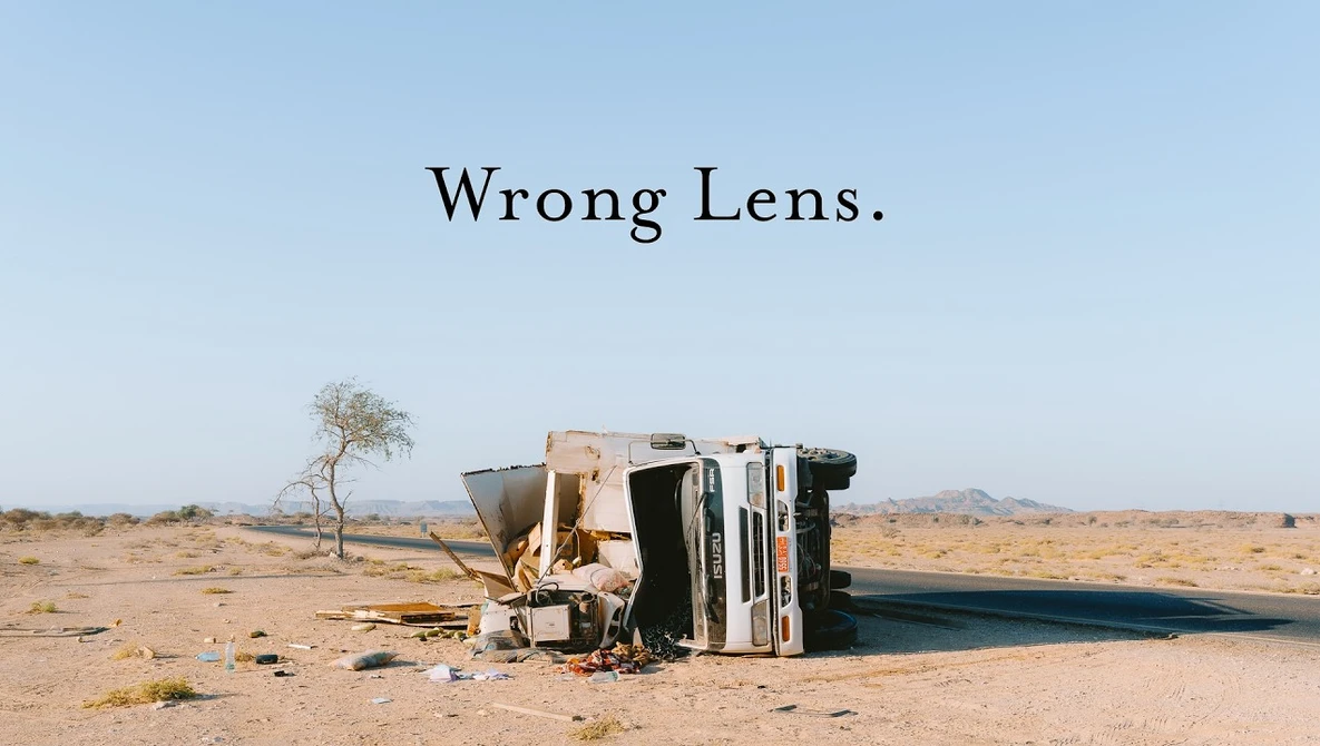 Overturned vehicle lying on its side in an arid desert landscape with sparse vegetation.