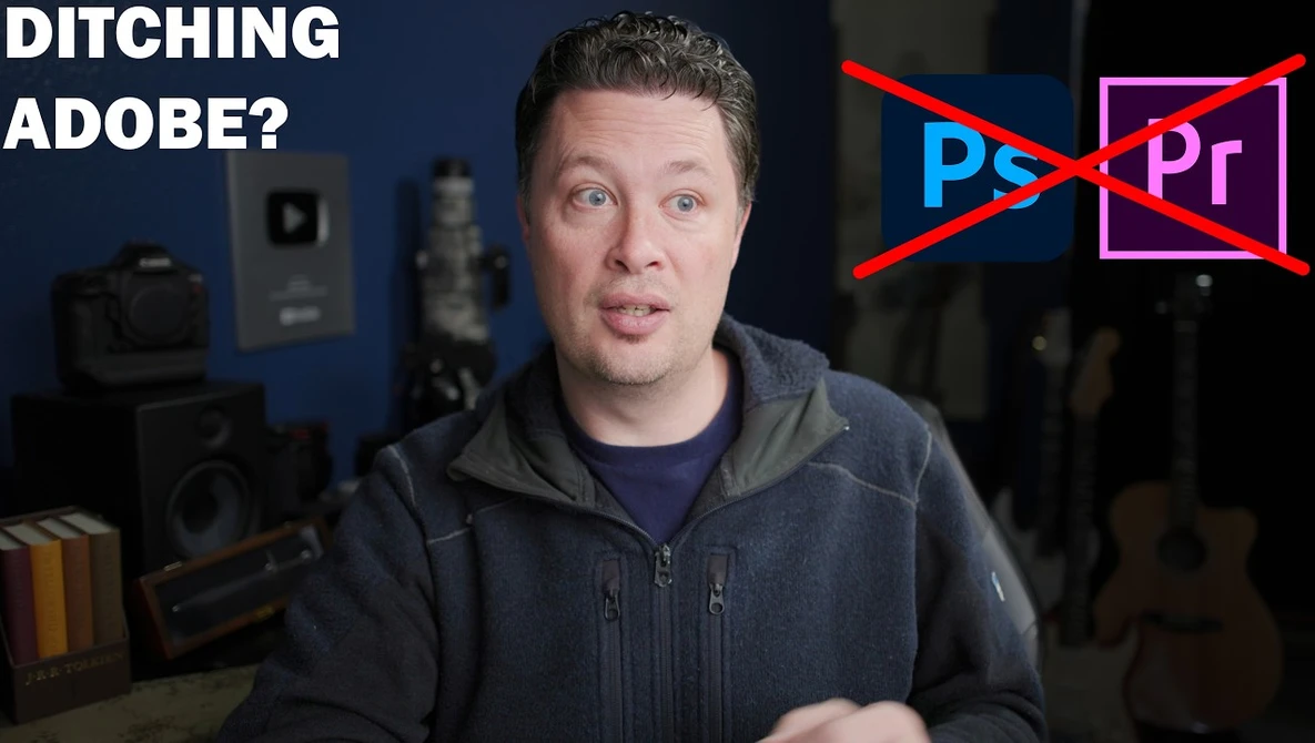 Man in dark hoodie speaking to camera with Adobe Creative Suite logos crossed out behind him.