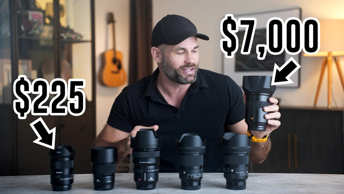 A man in a black cap and shirt displays five camera lenses arranged on a table, each labeled with prices ranging from $225 to $7,000.