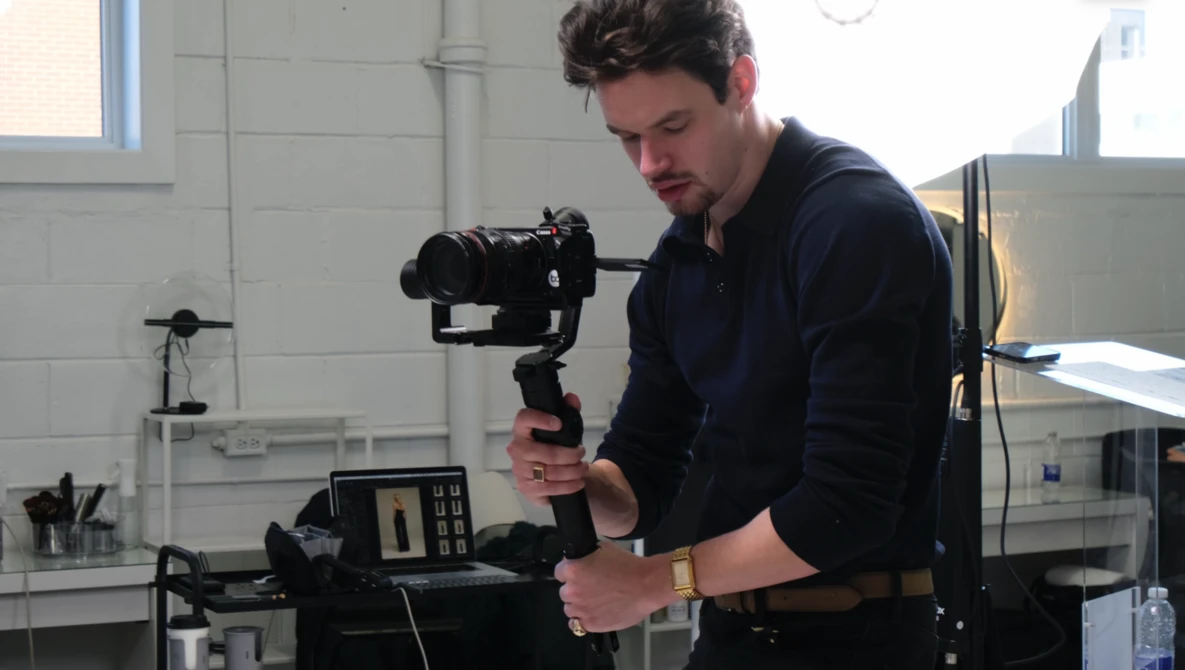 Videographer operating a motorized gimbal stabilizer in a bright studio space