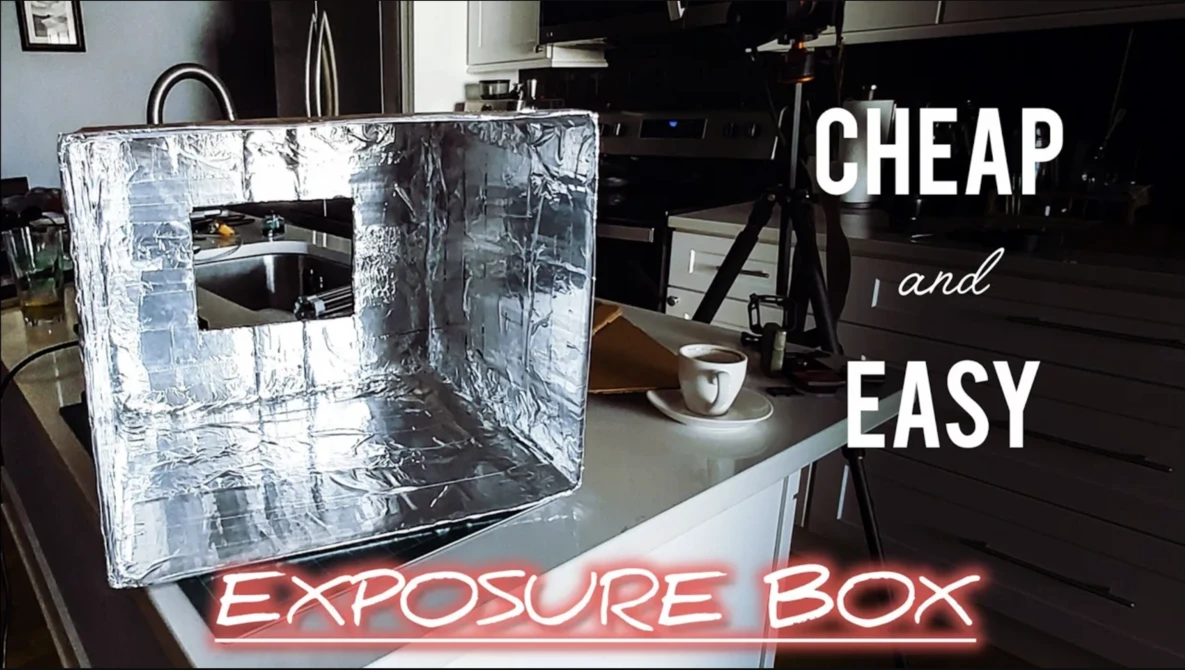 DIY photography exposure box made from white insulation material and aluminum foil on a kitchen counter.