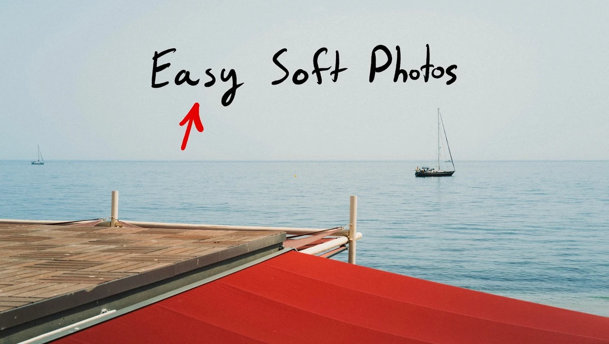 Wooden dock with red awning extending into calm blue water with sailboats in distance.