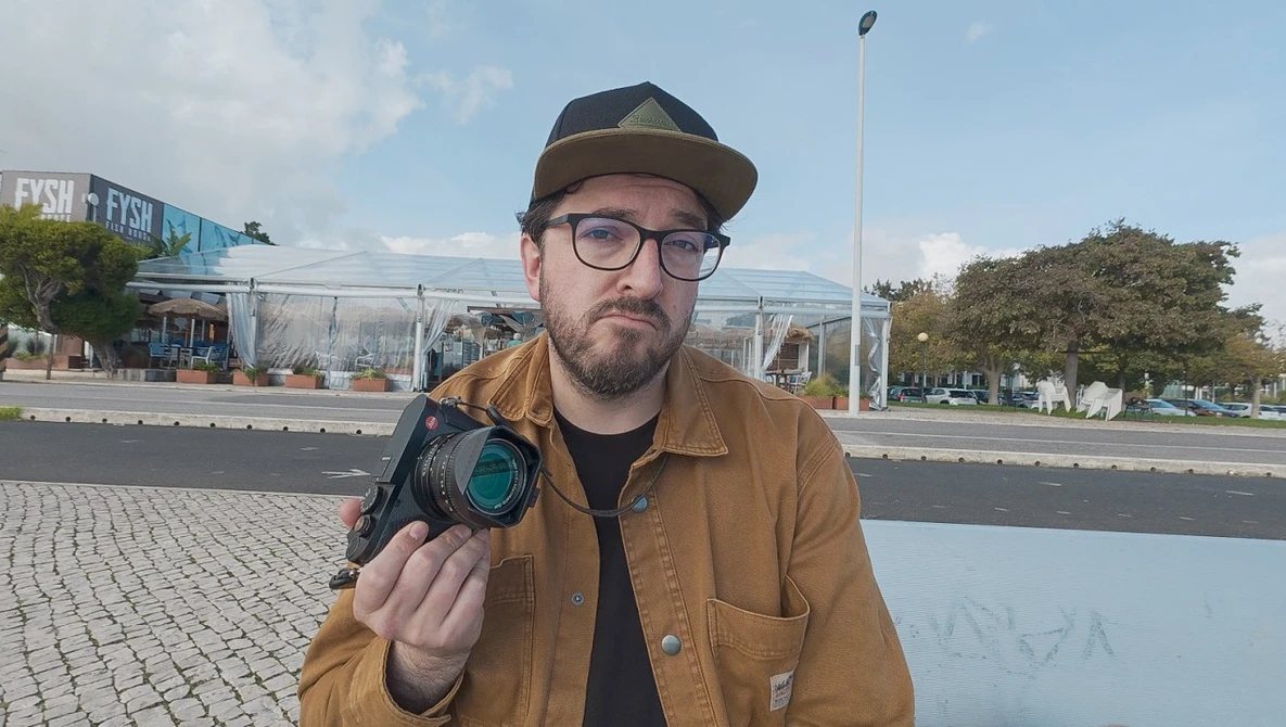 Photographer holding a thermal imaging camera while posing outdoors in urban setting.