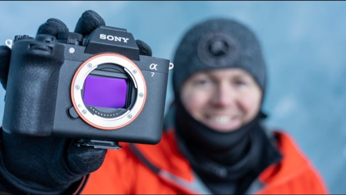Sony a7 mirrorless camera with sensor visible, held up to display purple filter coating.