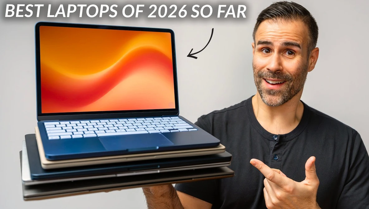 Man gesturing toward a stack of laptops with orange gradient display wallpaper visible on top model.