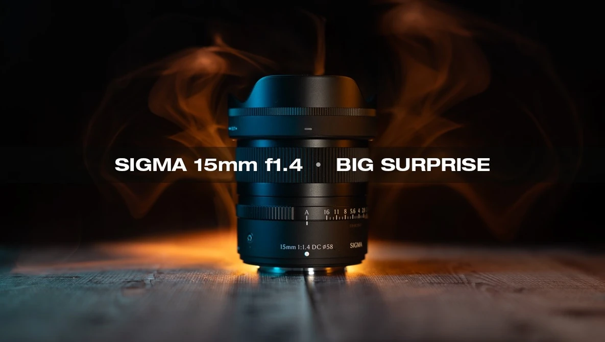 Sigma 15mm f1.4 lens with blue and black coloring positioned on reflective surface with warm atmospheric lighting and smoke effect in background.