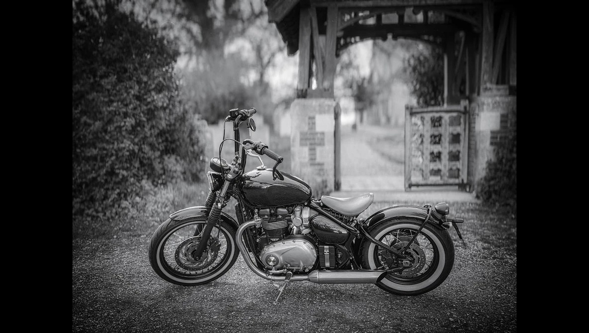 Classic motorcycle parked on a street with traditional Asian architecture in the background.