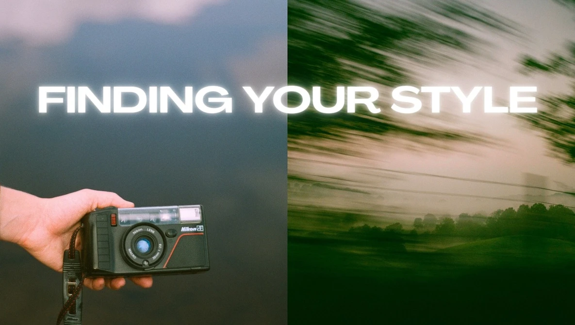 Hand holding a vintage rangefinder camera against a blurred mountainous landscape background.