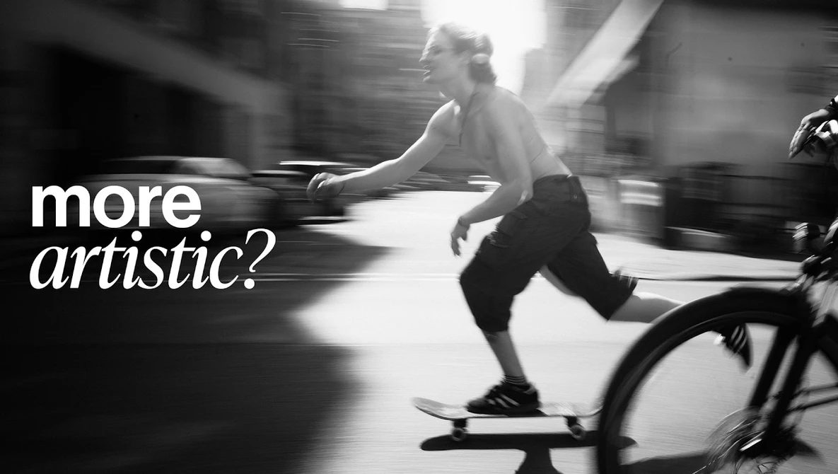 Black and white motion photo of a skateboarder mid-trick on an urban street with motion blur.