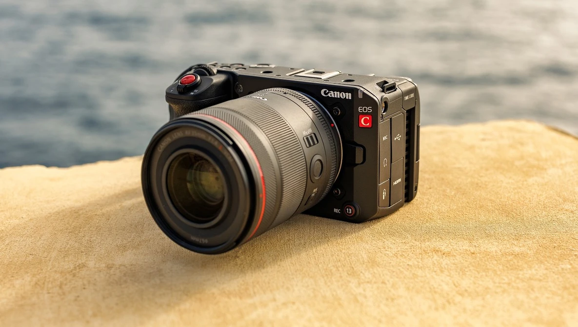 Canon EOS R5C mirrorless camera with RF lens on sandy beach with ocean in background.