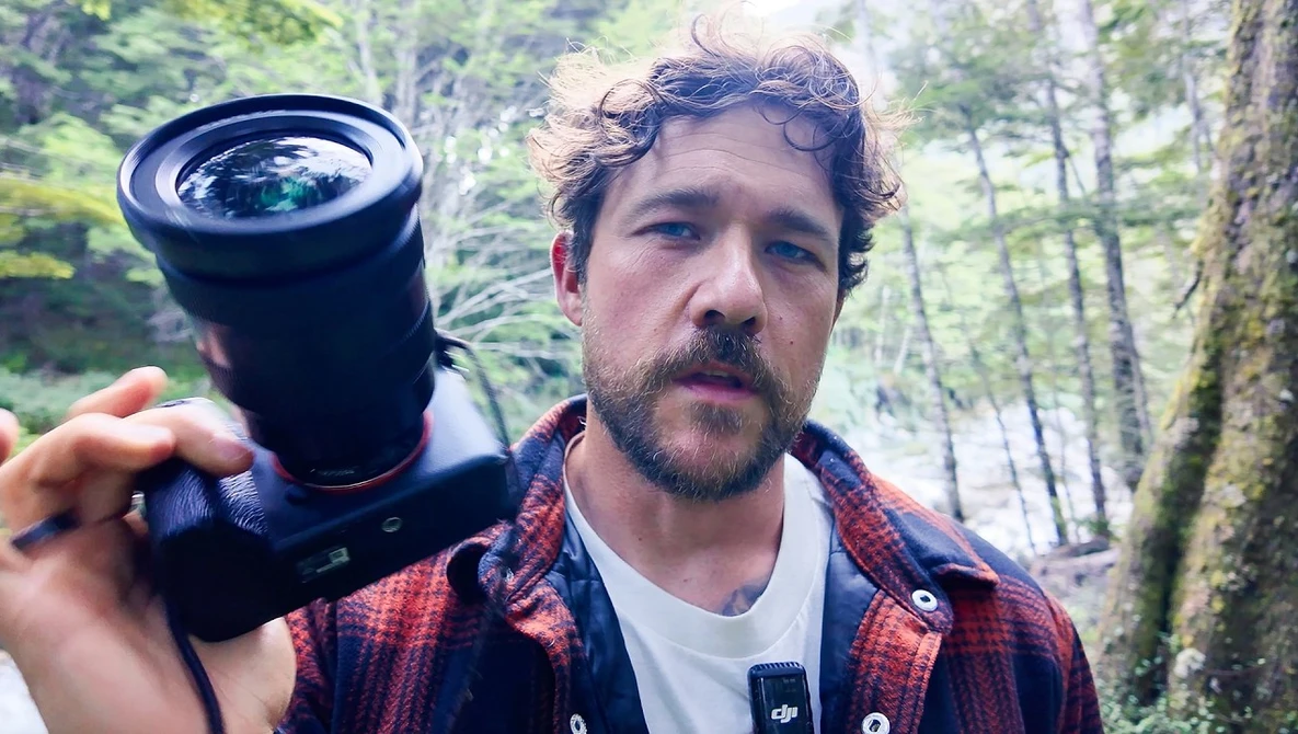 Photographer holding a wide-angle lens outdoors in a forest setting