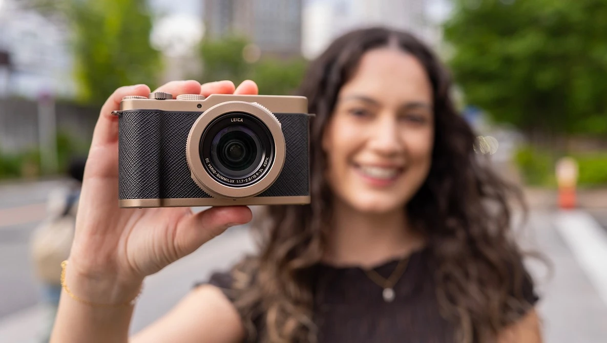 Woman holding a compact digital camera with black body and rose gold accents