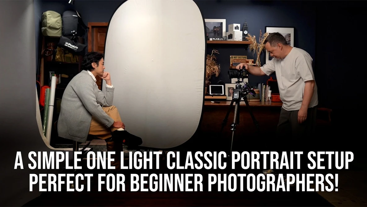Photographer and subject during one-light portrait setup with large reflector and camera on tripod