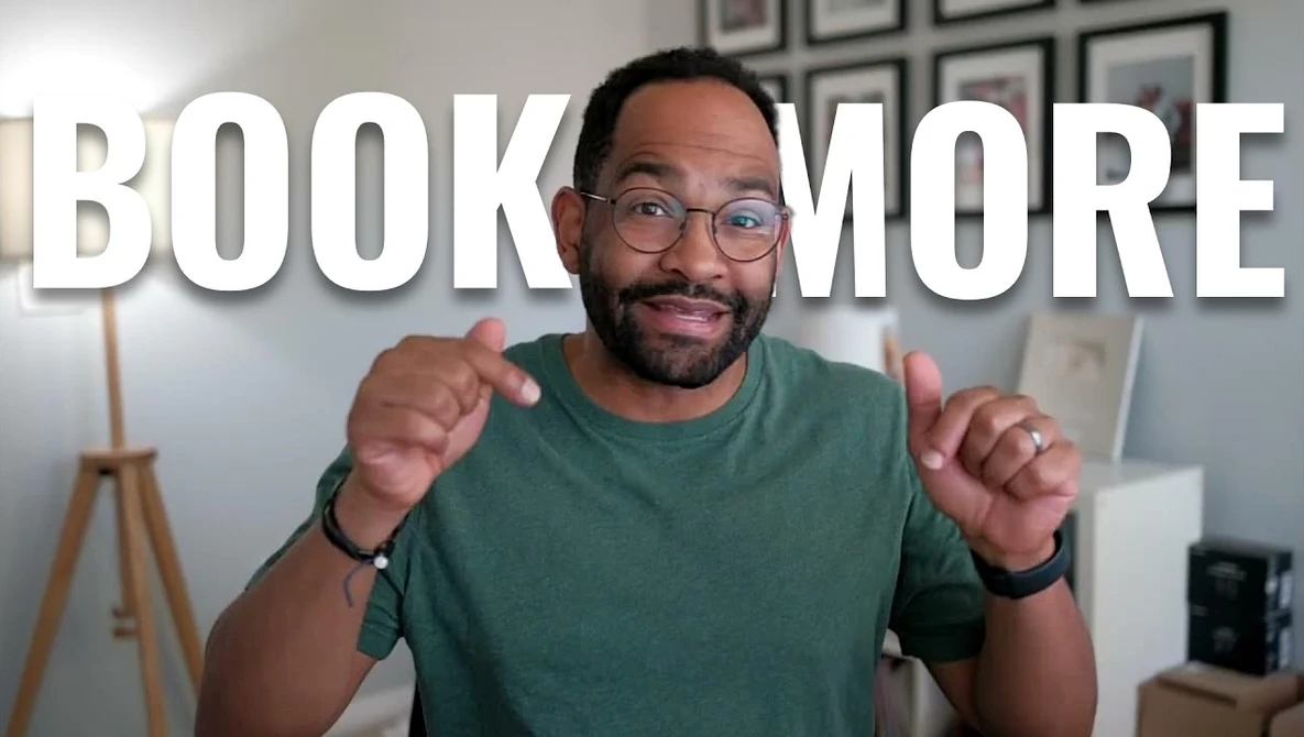 Man in green t-shirt and glasses pointing at camera with 'BOOK MORE' text overlay