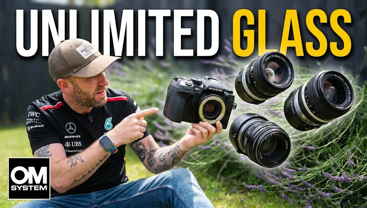 Photographer holding OM System camera with multiple lenses displayed outdoors