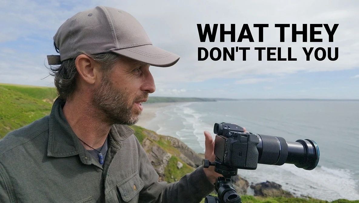 Photographer with telephoto lens on tripod overlooking coastal cliffs and ocean waves