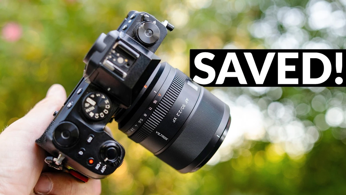 Mirrorless camera with attached lens held in hand against blurred green background