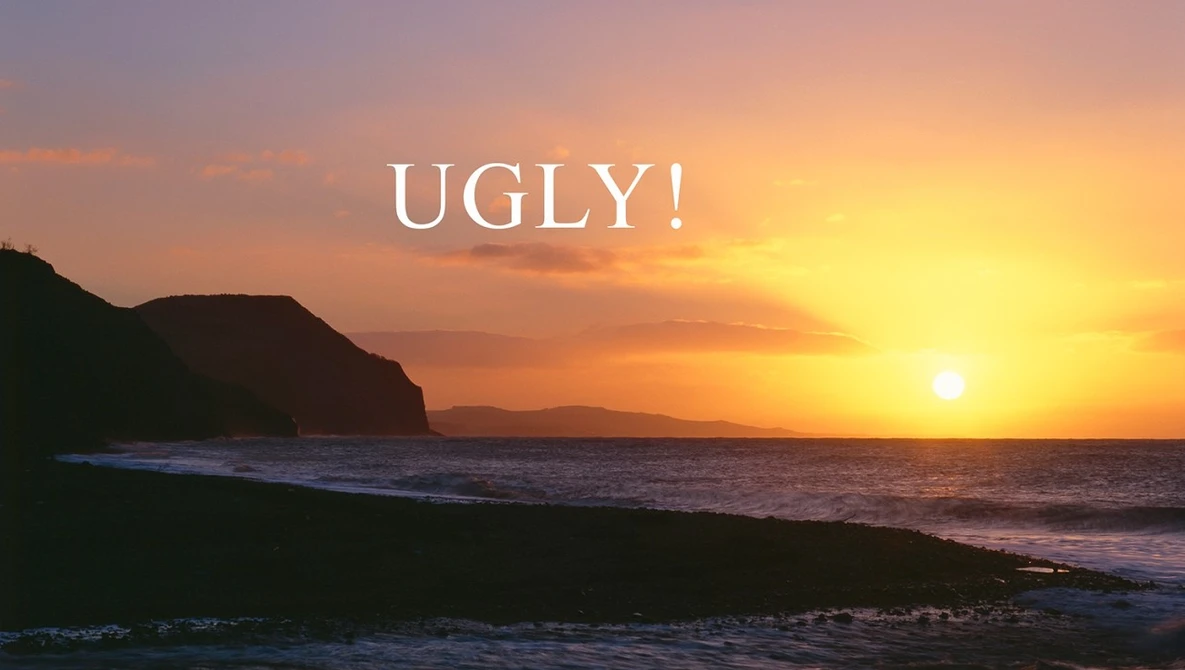 Dramatic golden sunset over a dark beach with rocky headland silhouettes