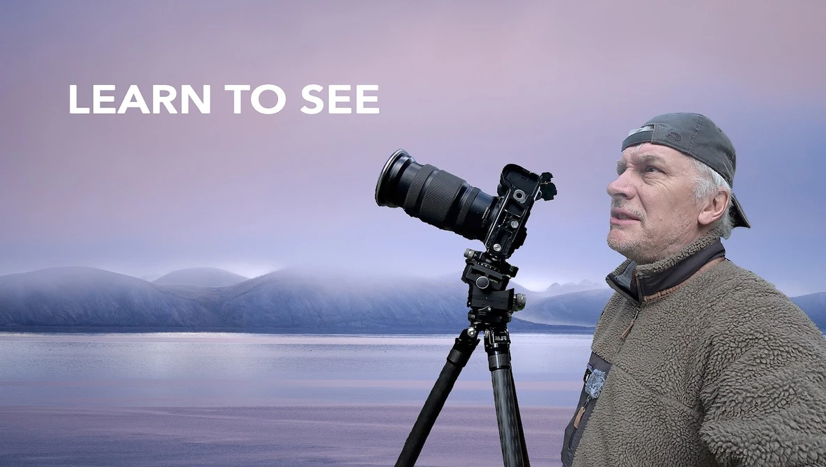 Photographer with telephoto lens on tripod overlooking misty lake landscape at dawn