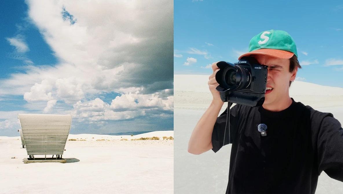 Photographer holding camera in desert landscape beside minimalist white structure