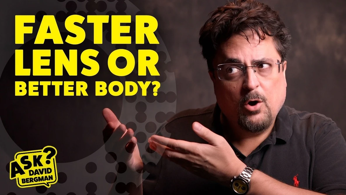 Man with glasses and beard gesturing while discussing camera equipment choice