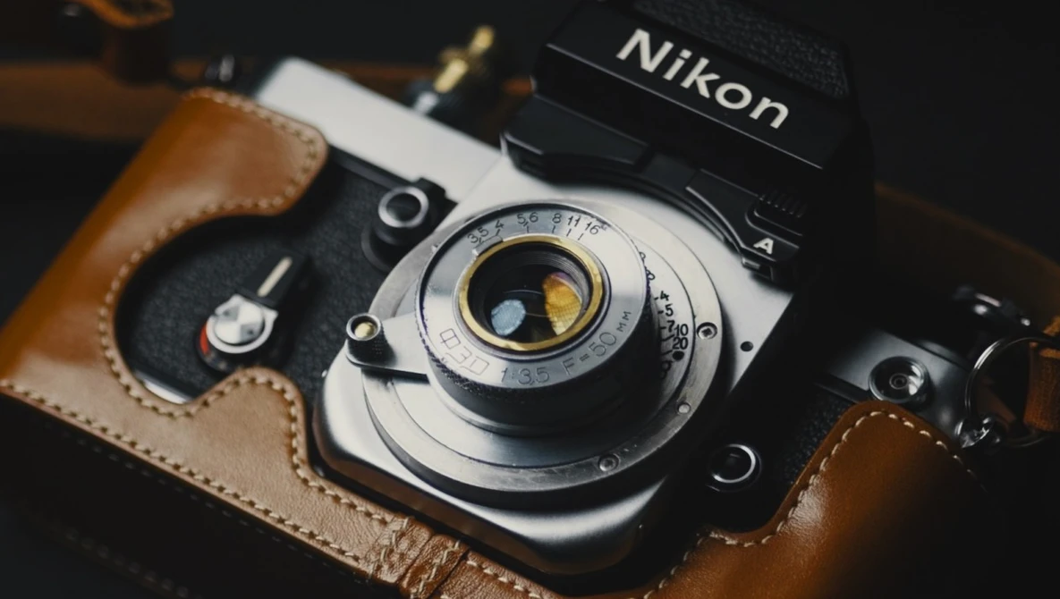 Nikon film camera with brown leather case and vintage lens detail
