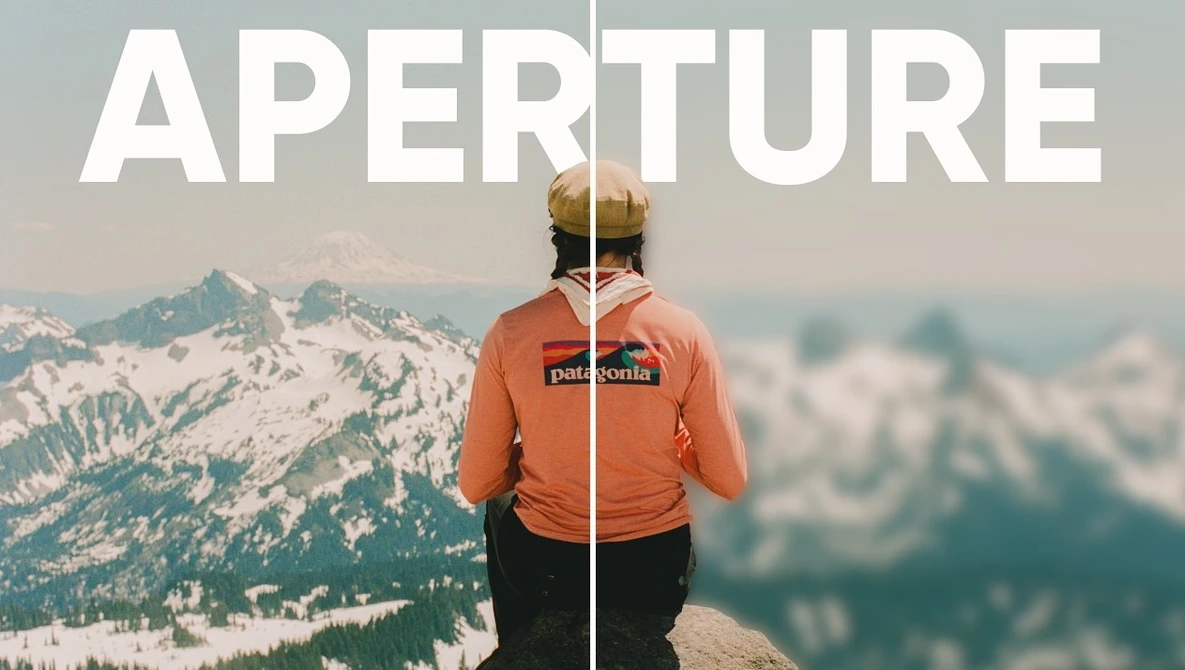 Person in orange Patagonia jacket standing on mountain ridge overlooking snowy peaks
