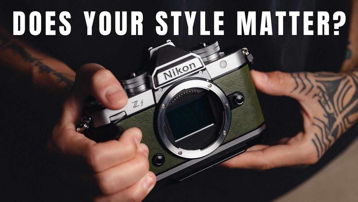 Person holding a vintage Nikon FM2 film camera with olive-green leather body and visible tattoos on their hands and arms