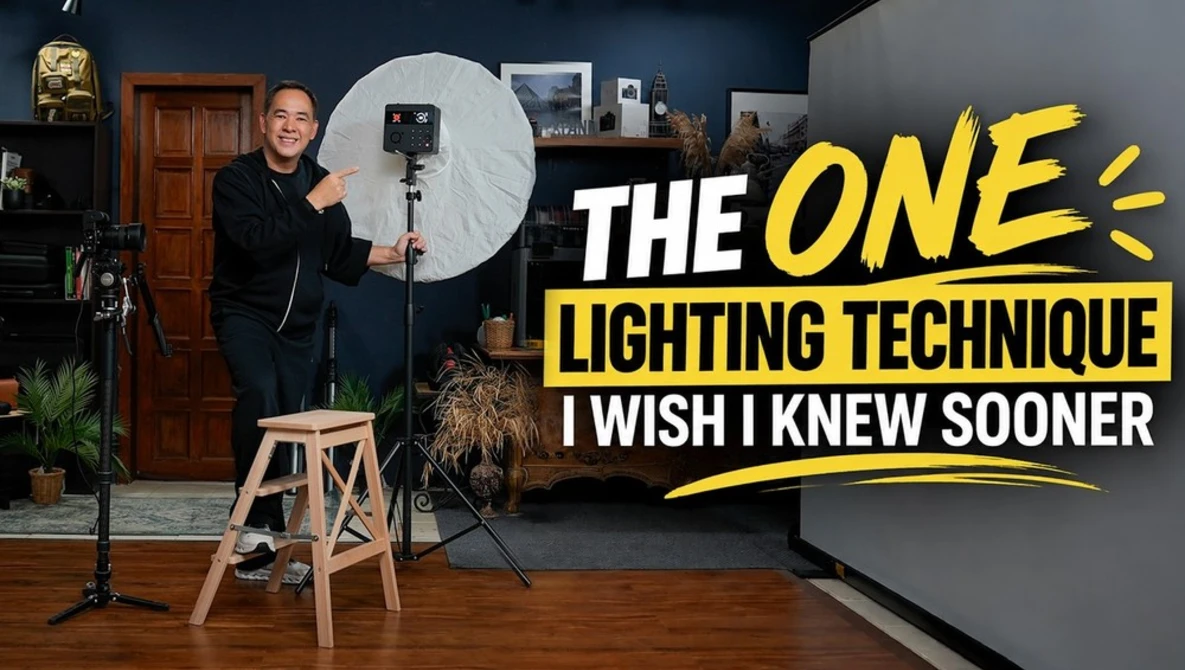 Photographer holding a large white reflector in a studio with studio lighting setup and wooden stool
