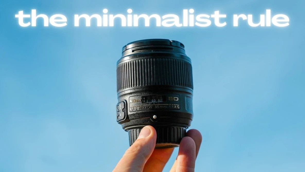 Hand holding a telephoto camera lens against a clear blue sky