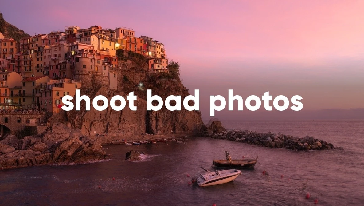 Coastal village perched on clifftop at sunset with boats in calm water below