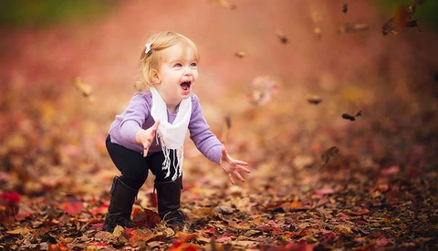 excited girl tossing leaves