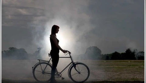 silhouette of girl standing beside bike