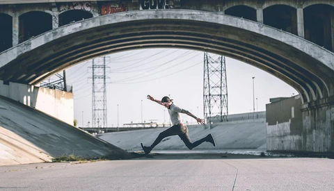 man taking long stride under urban overpass