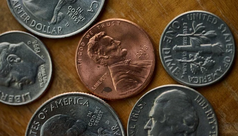 Assorted U.S. coins arranged on a wooden surface, including pennies, dimes, and quarters.