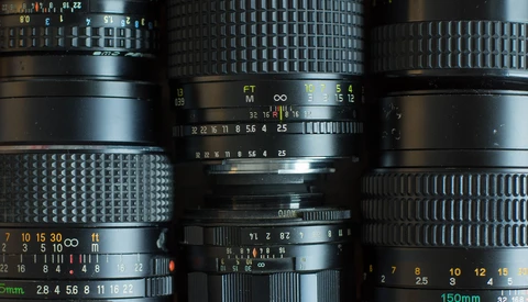 Overhead flat lay of vintage camera lenses with visible aperture and focus markings.