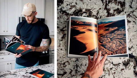 Photographer reviewing printed photo spreads of desert landscapes with warm orange tones.