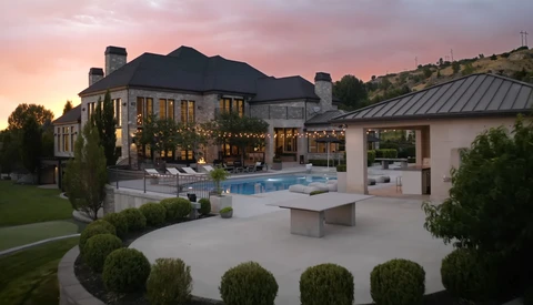 Luxury home exterior at twilight with illuminated windows, swimming pool, and manicured landscaping.