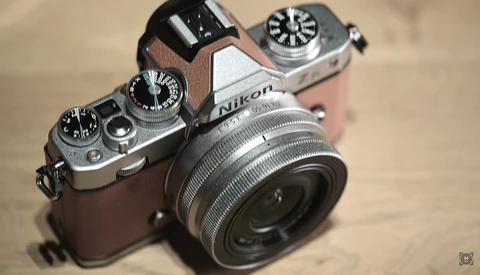 Nikon rangefinder camera with chrome and brown leather body, vintage lens attached, viewed from above on a neutral surface.