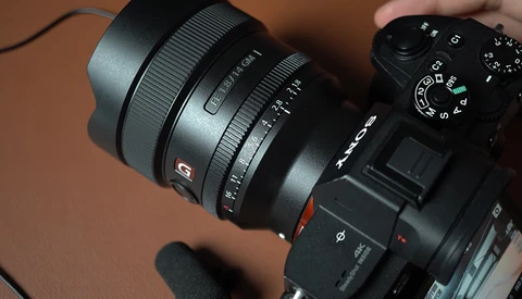Sony mirrorless camera with wide-angle zoom lens attached, shown against a brown background.