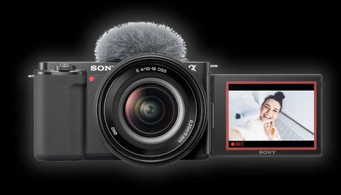 Sony mirrorless camera with attached microphone, flip-out LCD screen displaying video recording interface.