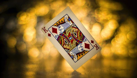 King of diamonds playing card tilted against golden bokeh background.
