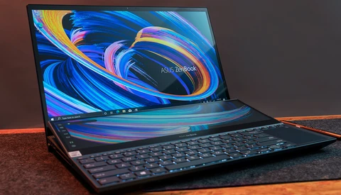 ASUS ZenBook laptop with dual displays showing colorful blue and orange swirl wallpaper design.