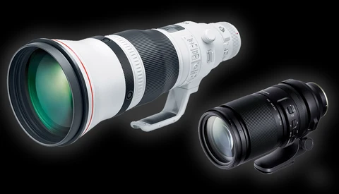 White telephoto lens and black telephoto lens displayed side-by-side against a dark background.