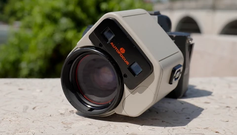 Vintage thermal imaging camera with cream-colored body and black lens on stone surface.
