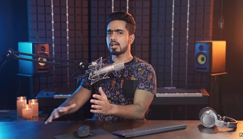 Male podcaster speaking into a large-diaphragm microphone in a professionally lit recording studio.