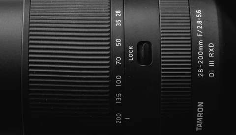Close-up of a Tamron 28-200mm zoom lens showing focal length markings and focus lock switch.